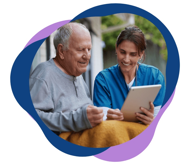 Senior man and young caregiver using a tablet together outdoors.