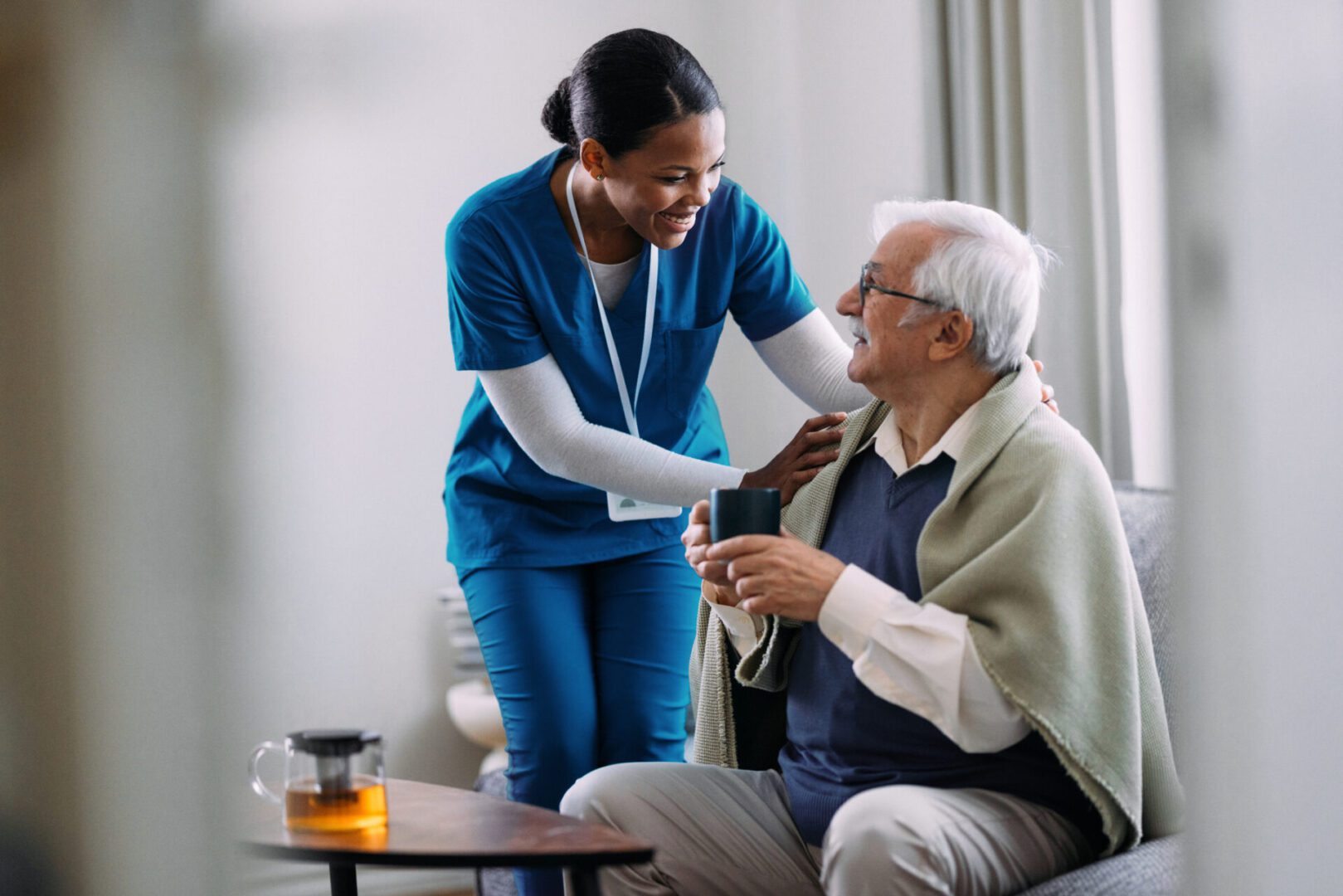 Nurse assisting elderly man with medication in a cozy home setting.